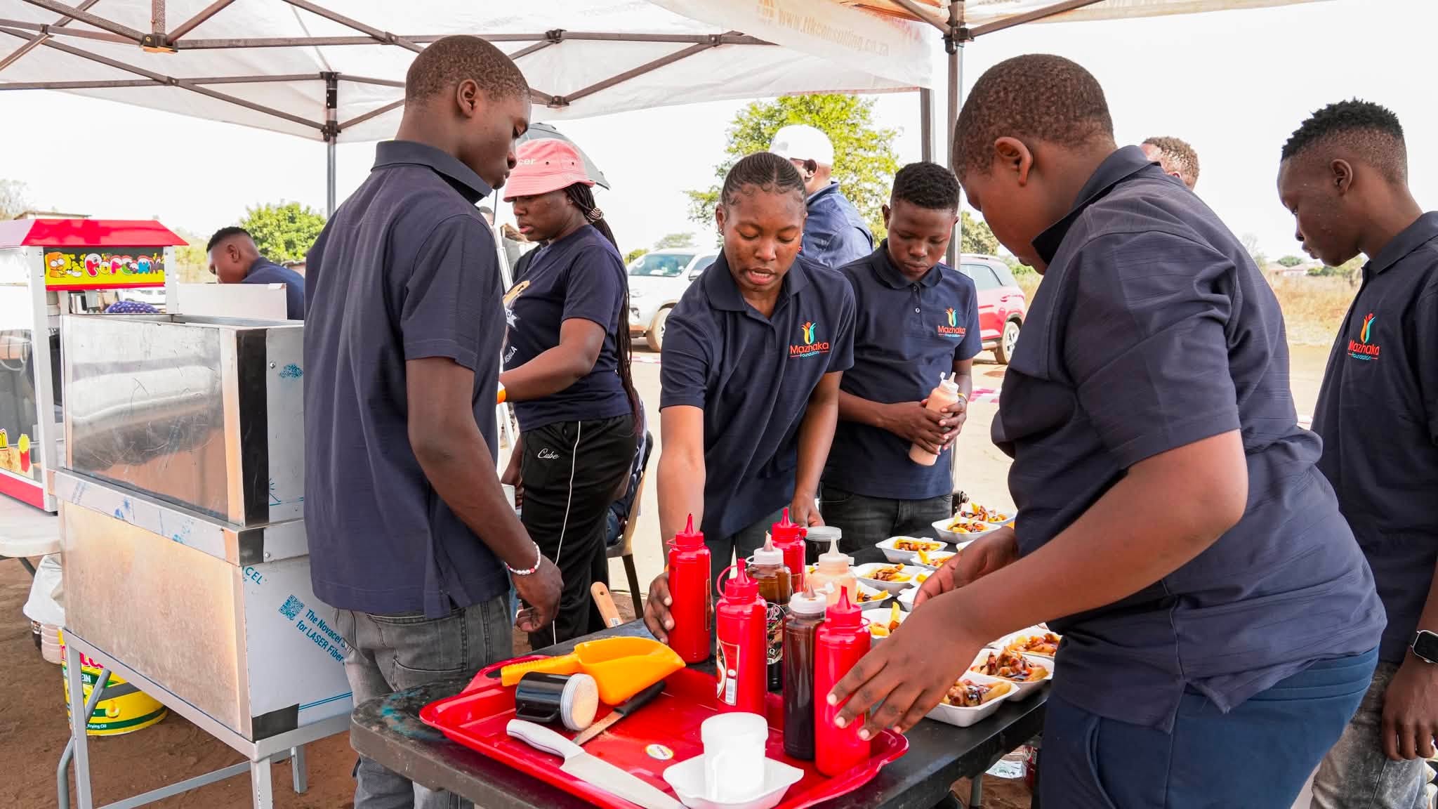 Volunteers prepare refreshments beneath the event tent