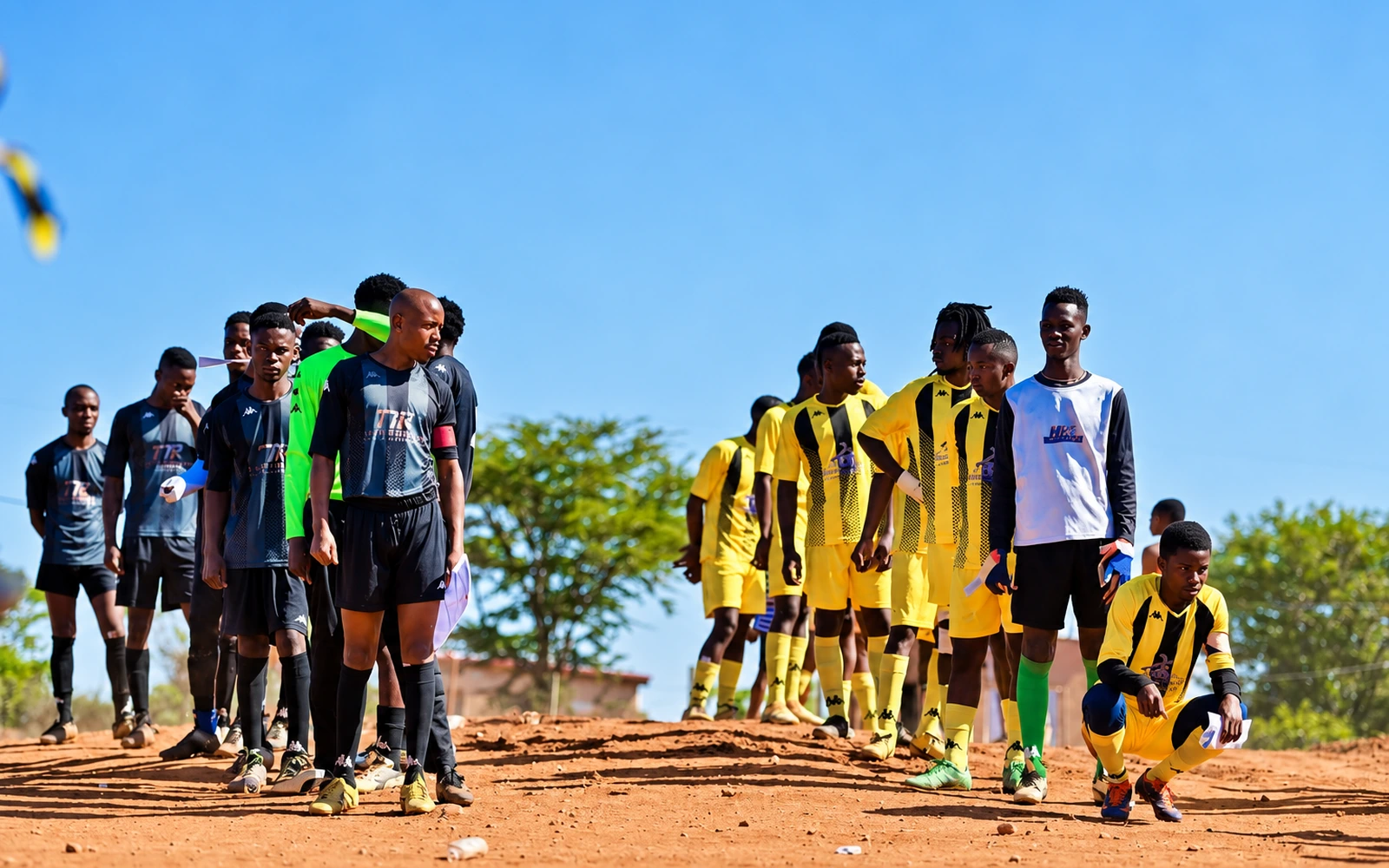 Young football players in black and yellow kits together on a football field