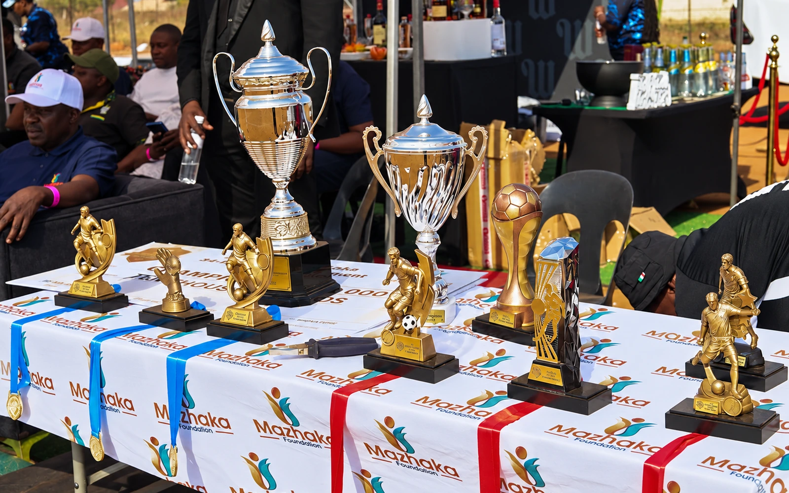 Football trophies and medals displayed on a Mazhaka Foundation table