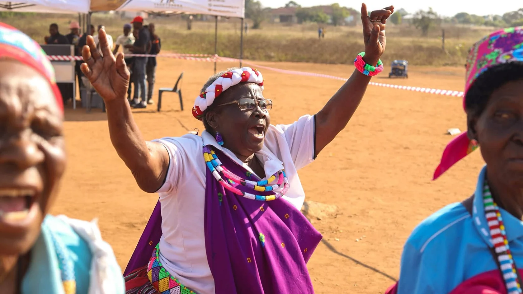 A woman wearing vibrant traditional dress celebrating with her hands raised