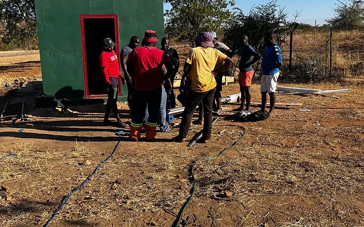 People gathered beside the green pump house