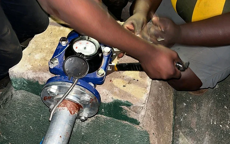 Hands working on a water pipe at the borehole installation