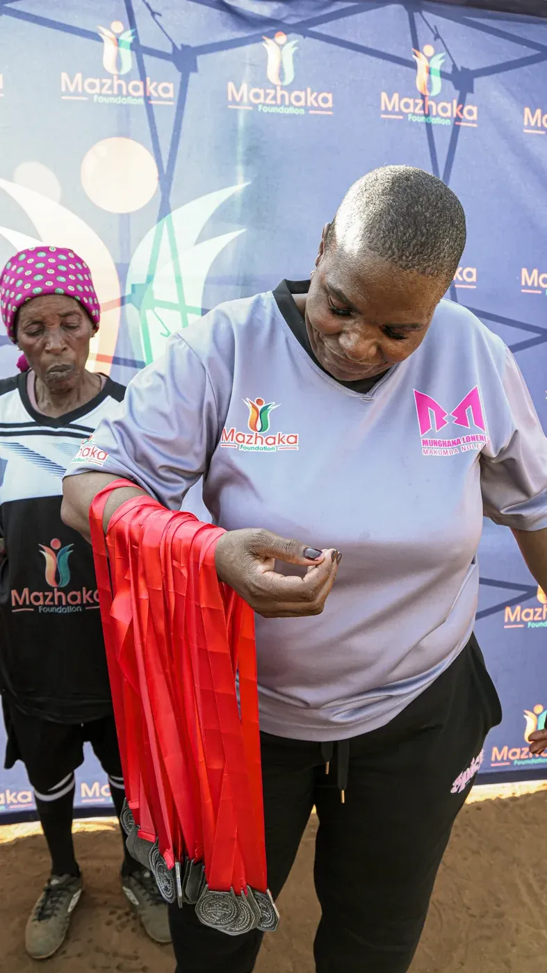 A volunteer holding a red garment in front of the Mazhaka Foundation backdrop
